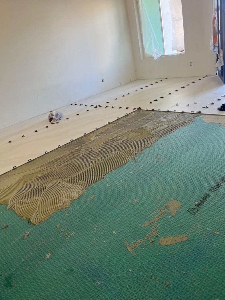 Tile being set over a waterproofing membrane with levelling clips in place